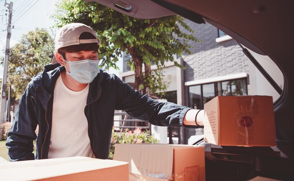 homem trabalhando na logística de entrega com máscara de proteção