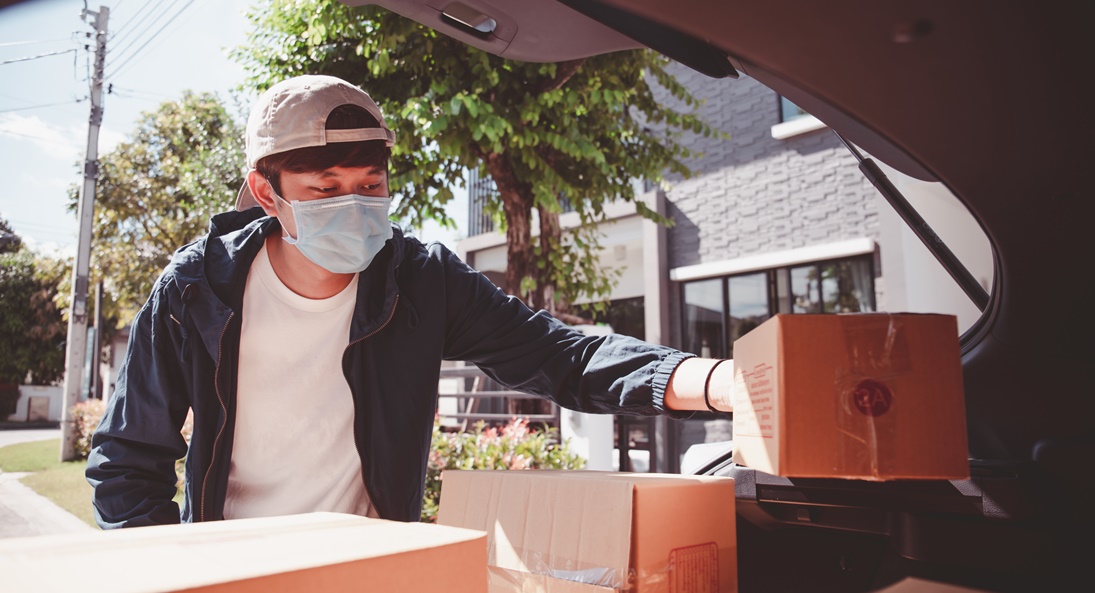 homem trabalhando na logística de entrega com máscara de proteção